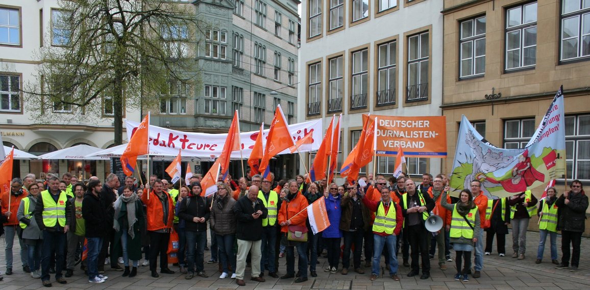 Demonstrierende des DJV-NRW halten Transparente und Fahnen hoch