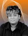 Ein Portraitbild von Abby Baheerathan vor orange-blauen Hintergrund. – 