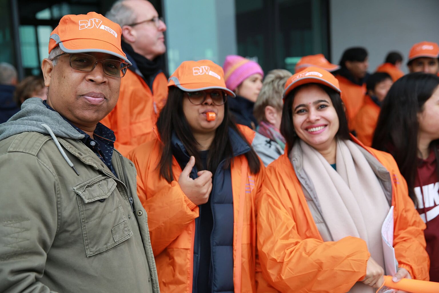 Drei Personen in Orange gekleidet streiken bei der Deutschen Welle für bessere Löhne. – 