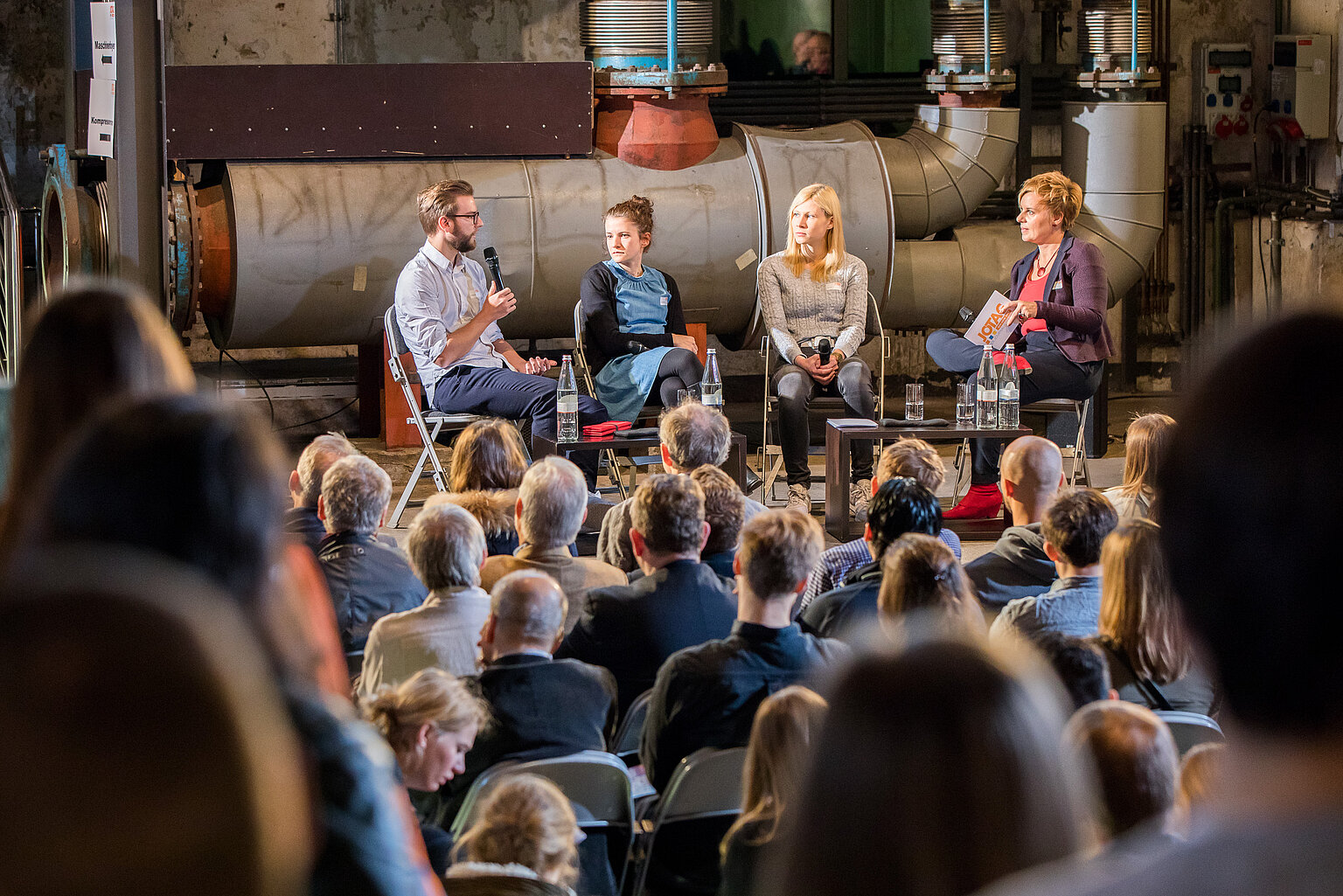 – Gaben die Startimpulse für den Journalistentag NRW 2017: (vlnr) Florian Gregorzyk, Sophie Burkhart, Marie Illner, Moderatorin Andrea Hansen. Blick in das Foyer der Gebläsehalle des Landschaftsparks Duisburg-Nord. Fotos: Udo Geisler